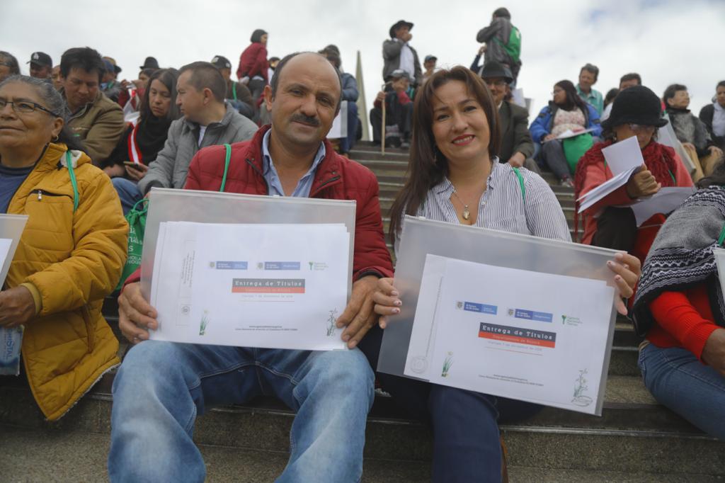 Un hombre y una mujer, felices al recibir cada uno sus títulos de propiedad y al rededor de ellos varios beneficiarios más del municipio de Ovejas.