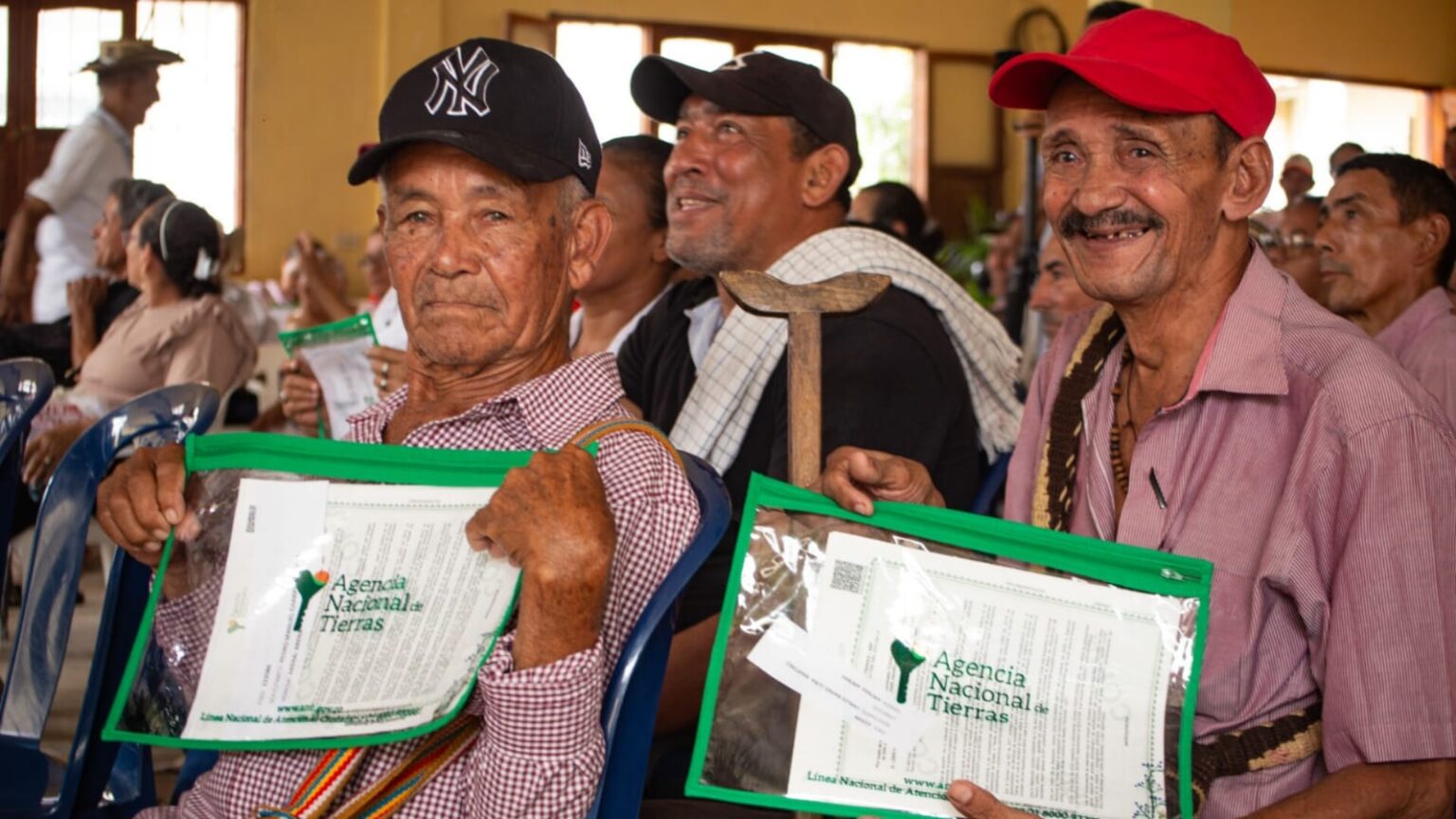 Dos señores campesinos sosteniendo sus títulos entregados por la ANT.