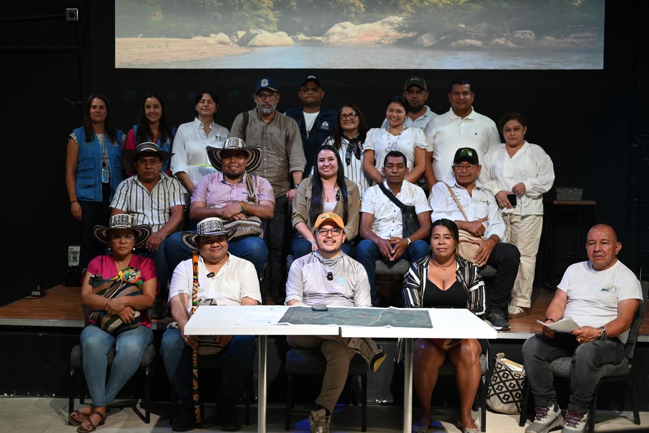 un-grupo-de-personas-sentadas-junto-director-ant-en-una-mesa-con-una-pantalla-de-proyecto