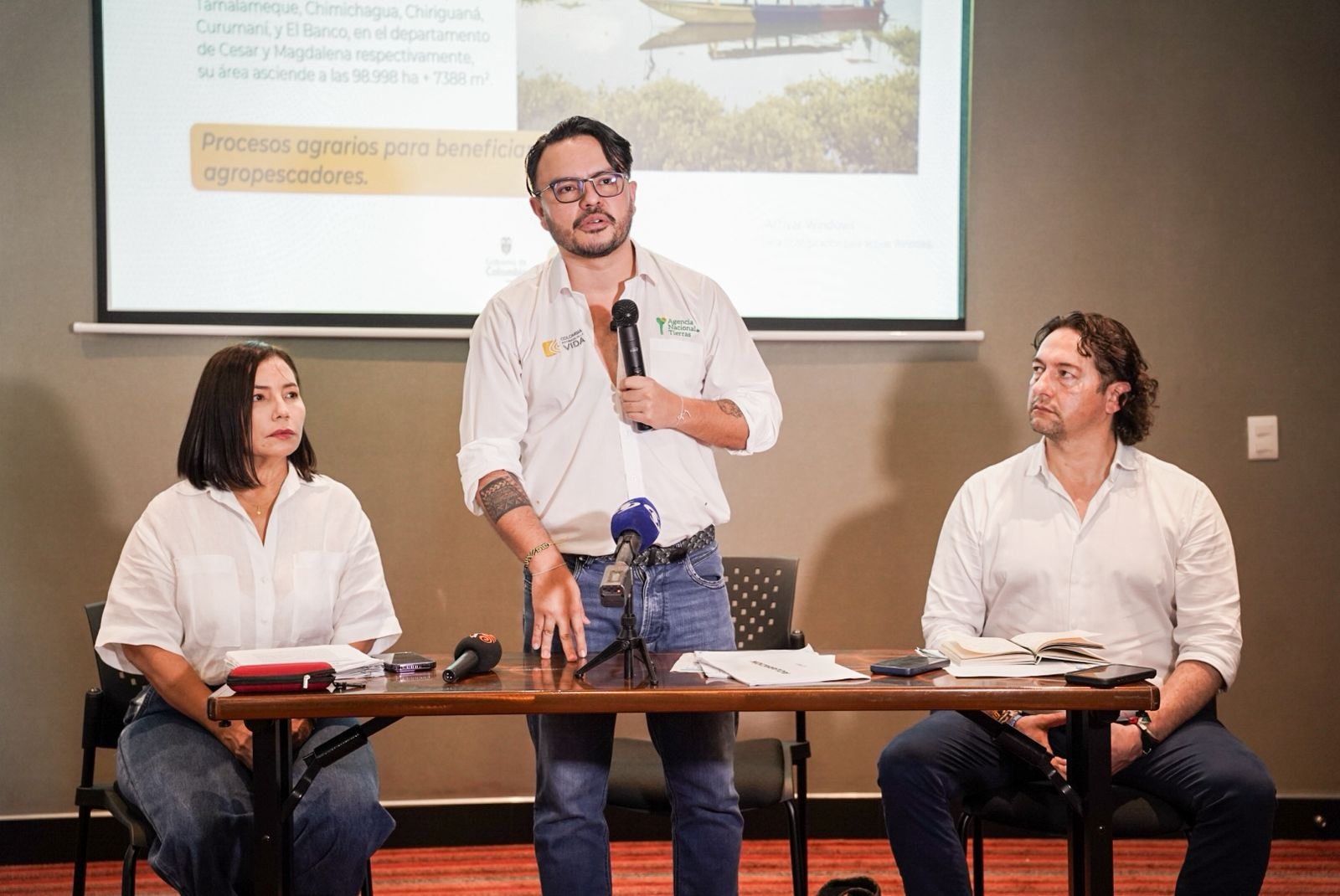 tres-personas-sentadas-en-una-mesa-con-una-pantalla-de-presentacion