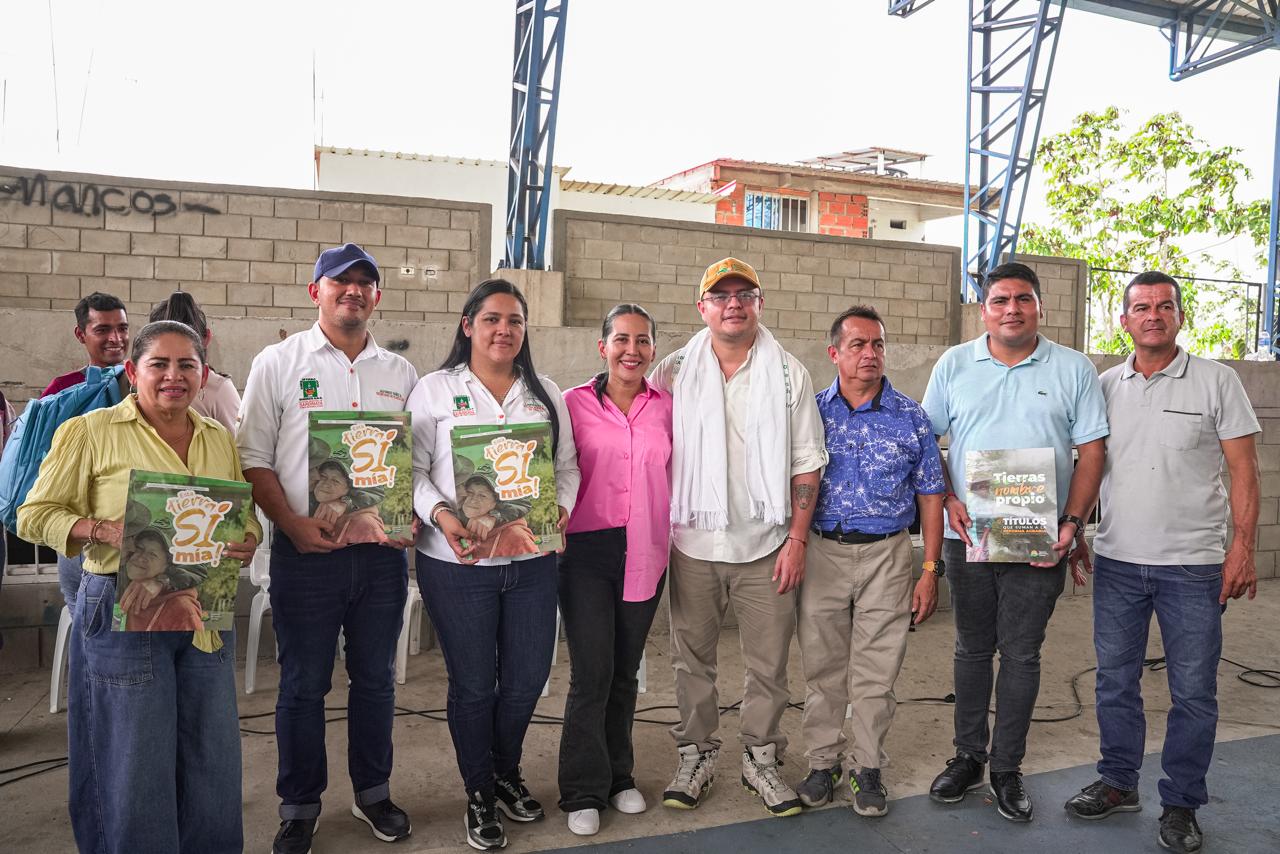 un-grupo-de-personas-parados-frente-a-un-edificio-con-titulos-de-tierras-en-las-manos