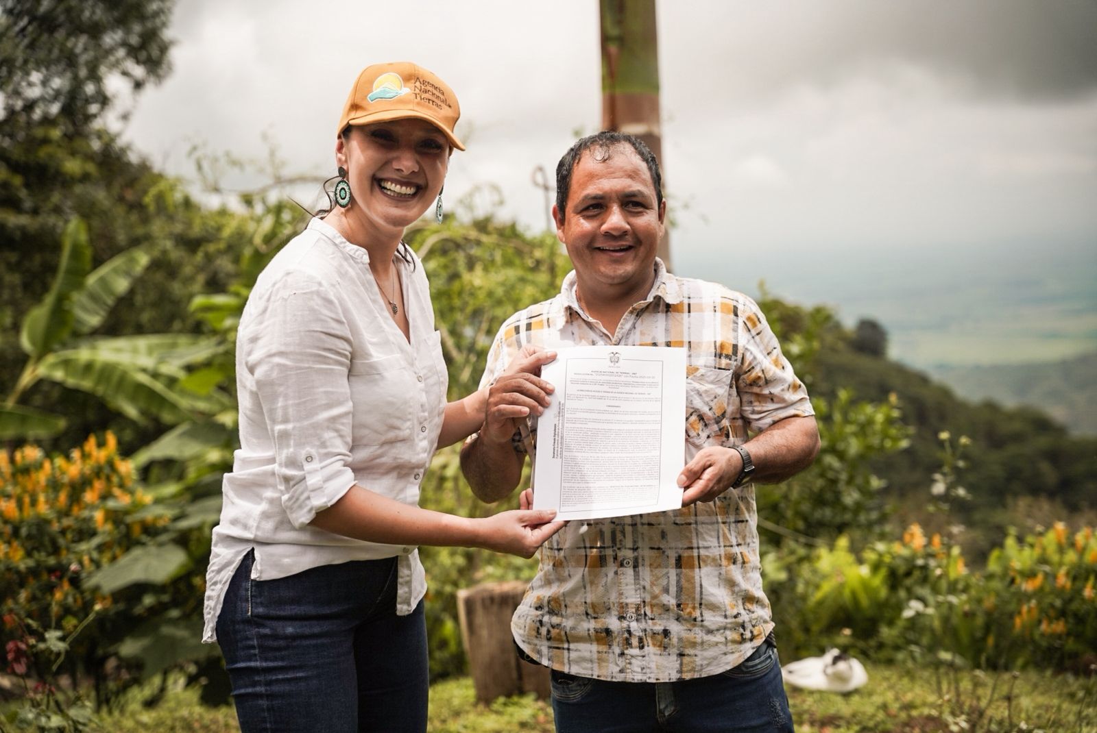 un-hombre-y-una-mujer-parados-frente-a-una-montana-sosteniendo-titulo-de-tierras