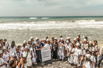 un-grupo-de-personas-paradas-en-la-playa-con-un-cartel