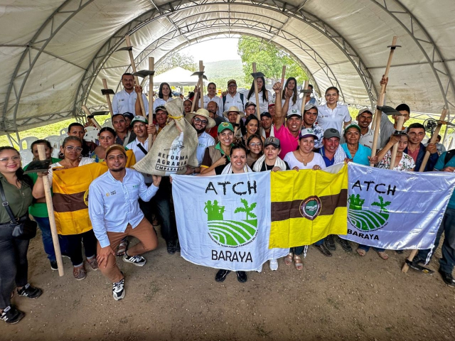 Beneficiarios de la entrega sosteniendo un asadón durante la ceremonia.