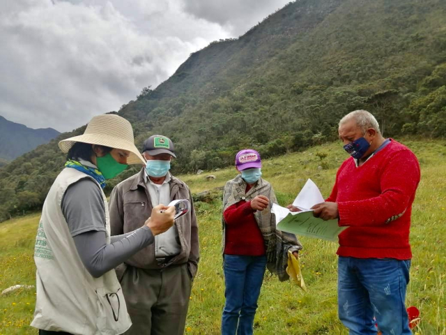 Grupo de personas revisando documentos en un terreno  en compañia de un funcionario de la ANT