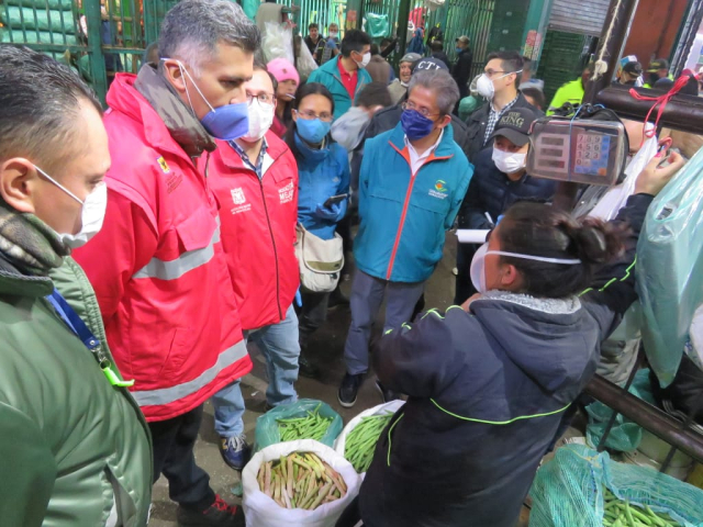 Dos funcionarios de la Alcaldía de Bogotá en compañía de varios comerciantes de Corabastos, realizando una jornada de verificación de precios y el abastecimiento de alimentos.