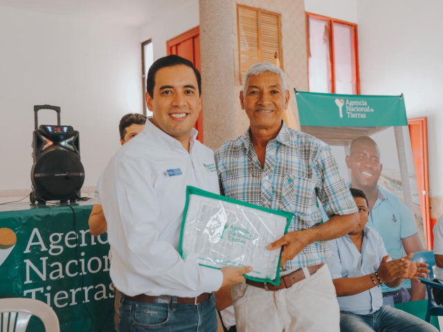 Aparecen dos personas, Campo Elías Vega, Subdirector de Tierras de la Nación, haciendo entrega del título de propiedad a Hernando Benítez, beneficiario de San Benito Abad, Sucre.