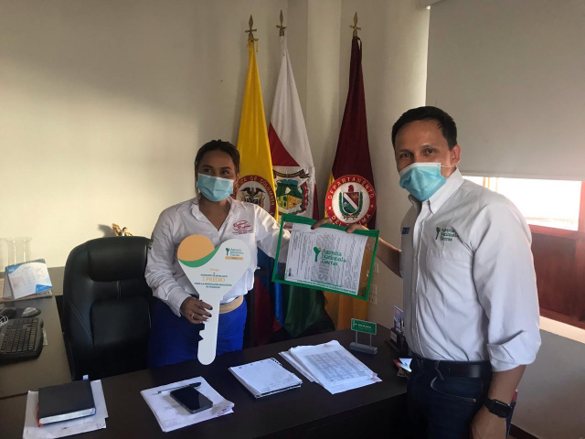 Dos funcionarios de la ANT mostrando un titulo de propiedad