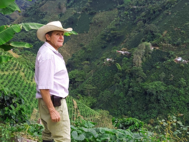 Señor campesino en las montañas donde hay algunas siembras.