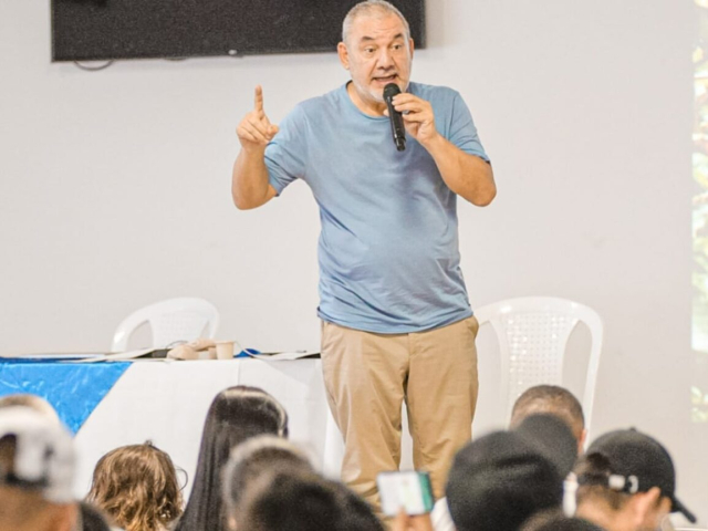Gerarrdo Vega hablando con un micrófono frente a algunas personas