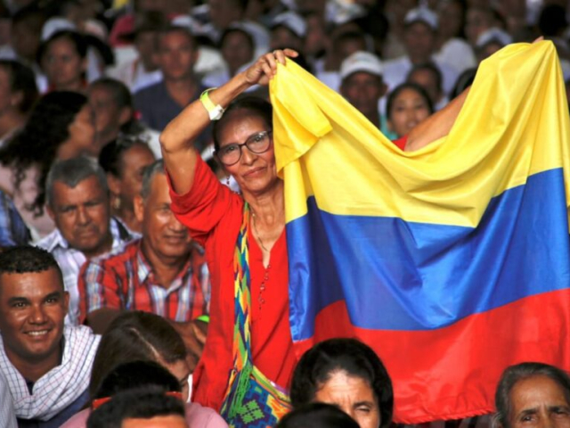 Mujer sosteniendo una bandera de Colombia en medio de la asamblea popular en Aguachica, Cesar.