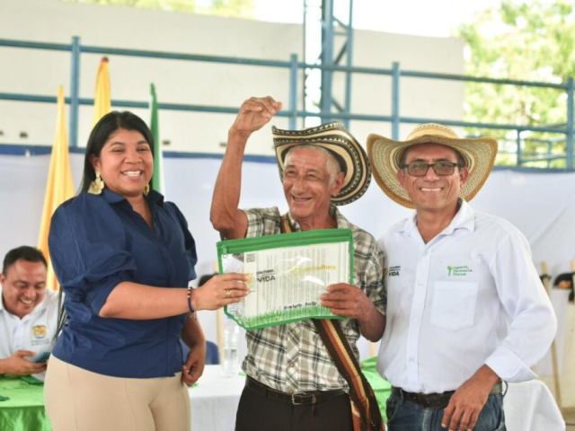 Campesino recibiendo su titulo de tierra por parte de funcionarios de la ant