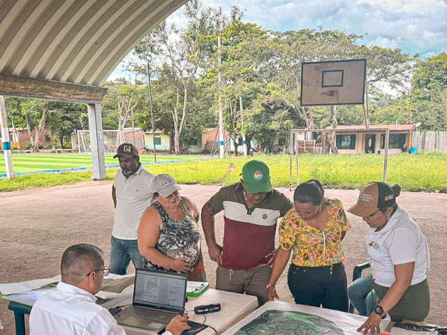 gente-de-pie-alrededor-de-una-mesa-con-una-computadora-porttil-y-pape