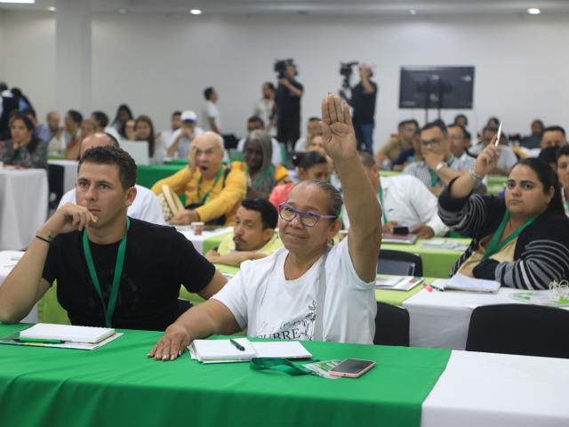 Mujer asistente levantando la mano para participar en la sesión.