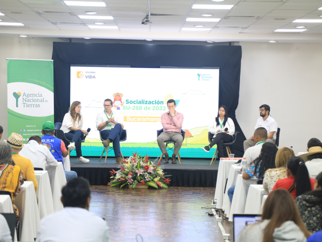 Cinco personas sentadas al frente del auditorio a manera de panel.