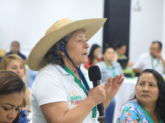 Mujer asistente con sombrero hablando por micrófono durante su intervención.