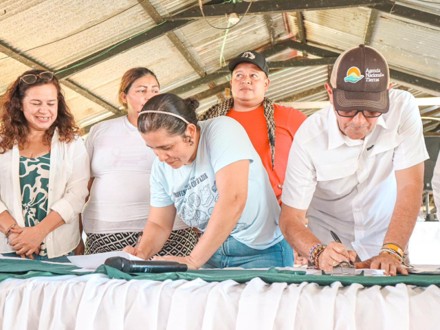 un-grupo-de-personas-paradas-alrededor-de-una-mesa-firmando-documentos