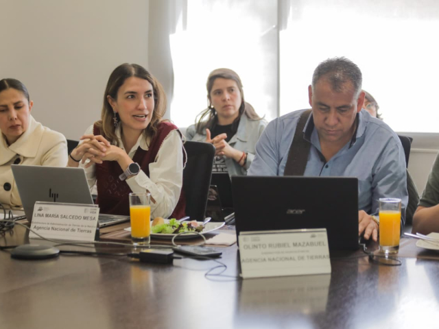 un-grupo-de-personas-sentadas-en-una-mesa-con-computadoras-portatiles