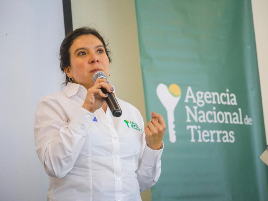 Myriam Martínez Cárdenas Directora de la ANT, aparece sola, con un micrófono en su mano derecha y de fondo un pendón con el logo de la ANT, informando sobre la activación de todos los canales digitales para atender las solicitudes de los usuarios, debido a la emergencia decretada por el Gobierno nacional por el Covid-19.