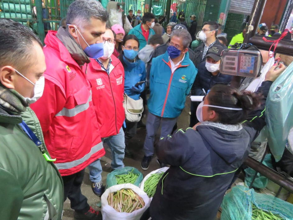 Dos funcionarios de la Alcaldía de Bogotá en compañía de varios comerciantes de Corabastos, realizando una jornada de verificación de precios y el abastecimiento de alimentos.