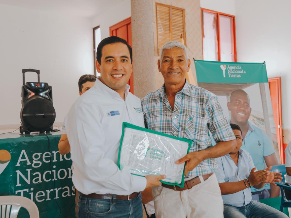 Aparecen dos personas, Campo Elías Vega, Subdirector de Tierras de la Nación, haciendo entrega del título de propiedad a Hernando Benítez, beneficiario de San Benito Abad, Sucre.
