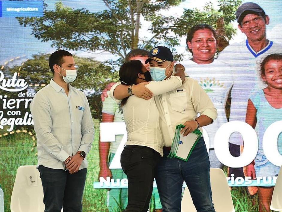 Ex presidente Ivan Duque abrazando a una mujer beneficiaria de la entrega de titulos junto a otros funcionarios