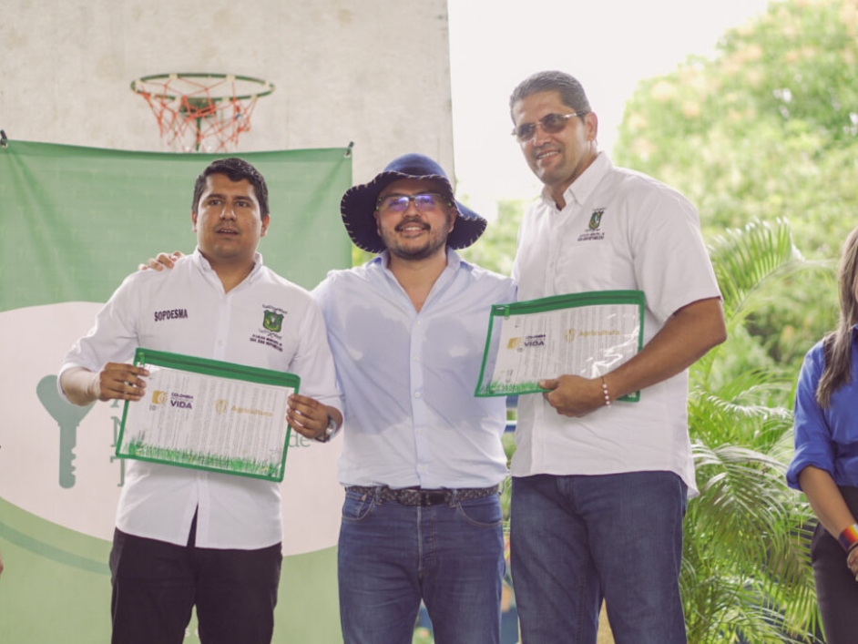 Tres personas, dos de ellas con sus títulos en mano.