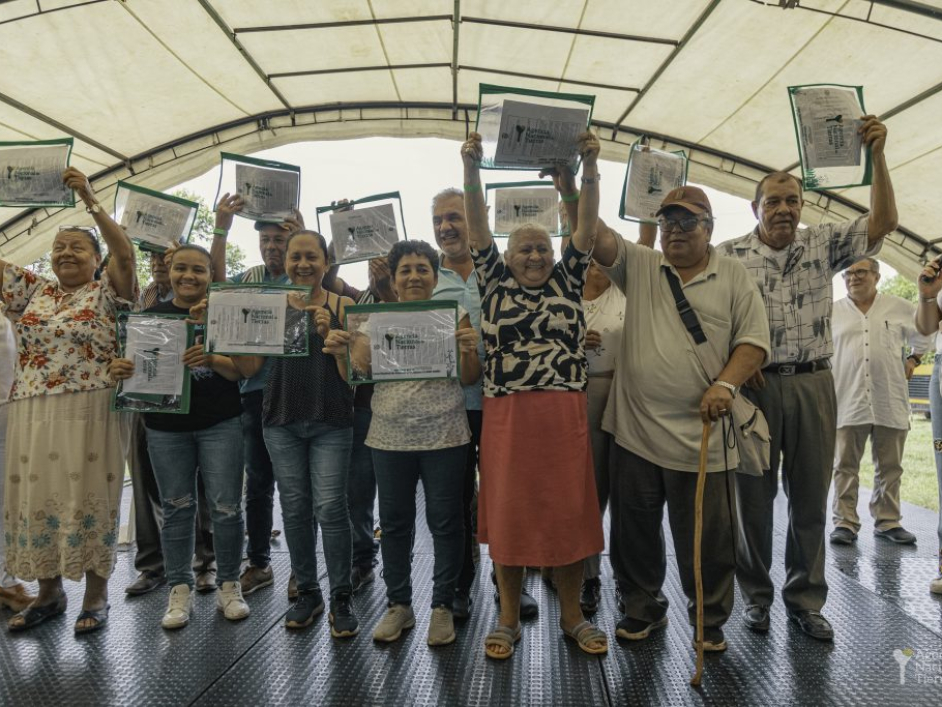 Beneficiados sosteniendo sus títulos de entrega de tierras.