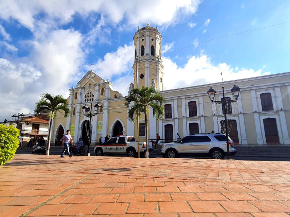 Catedral de Santa Ana – Ocaña, Norte de Santander. En frente de la iglesia dos camiones parqueadas una de la Policía y otra particular. De fondo el cielo azul con nubes blancas.