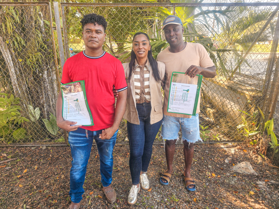 tres-personas-con-certificados-frente-a-una-cerca