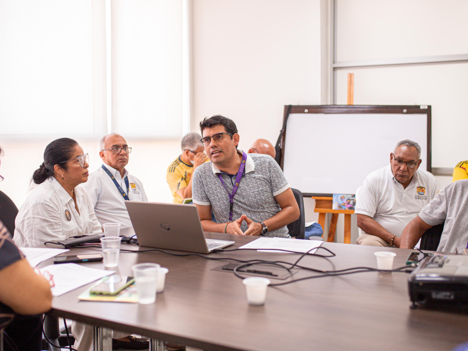un-grupo-de-personas-sentadas-alrededor-de-una-mesa-con-una-computadora